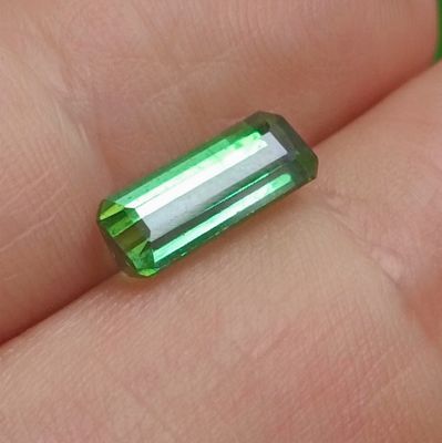 quelqu'un tient une tourmaline verte dans la main