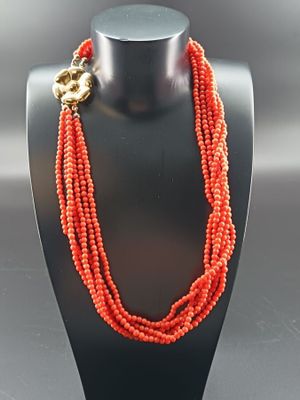 un gros plan d'un collier sur un mannequin, orné de perles rouges