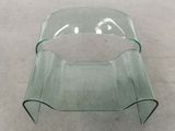 a glass table with a curved top on the floor