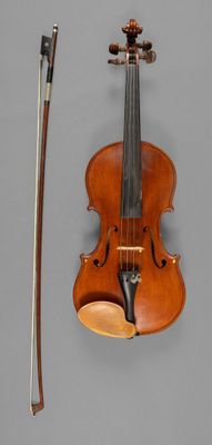 an old violin with a bow and a bow rest on a gray surface