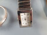 a silver watch sitting on a table next to other silver items