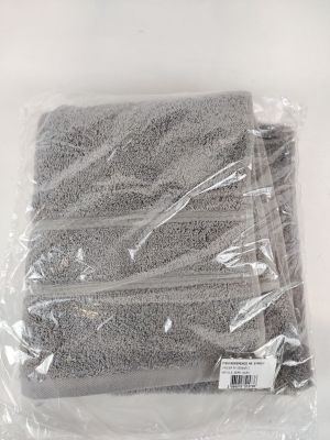 quatre serviettes grises emballées dans des sacs en plastique, posées sur une surface blanche
