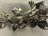 a silver brooch with flowers and leaves on it