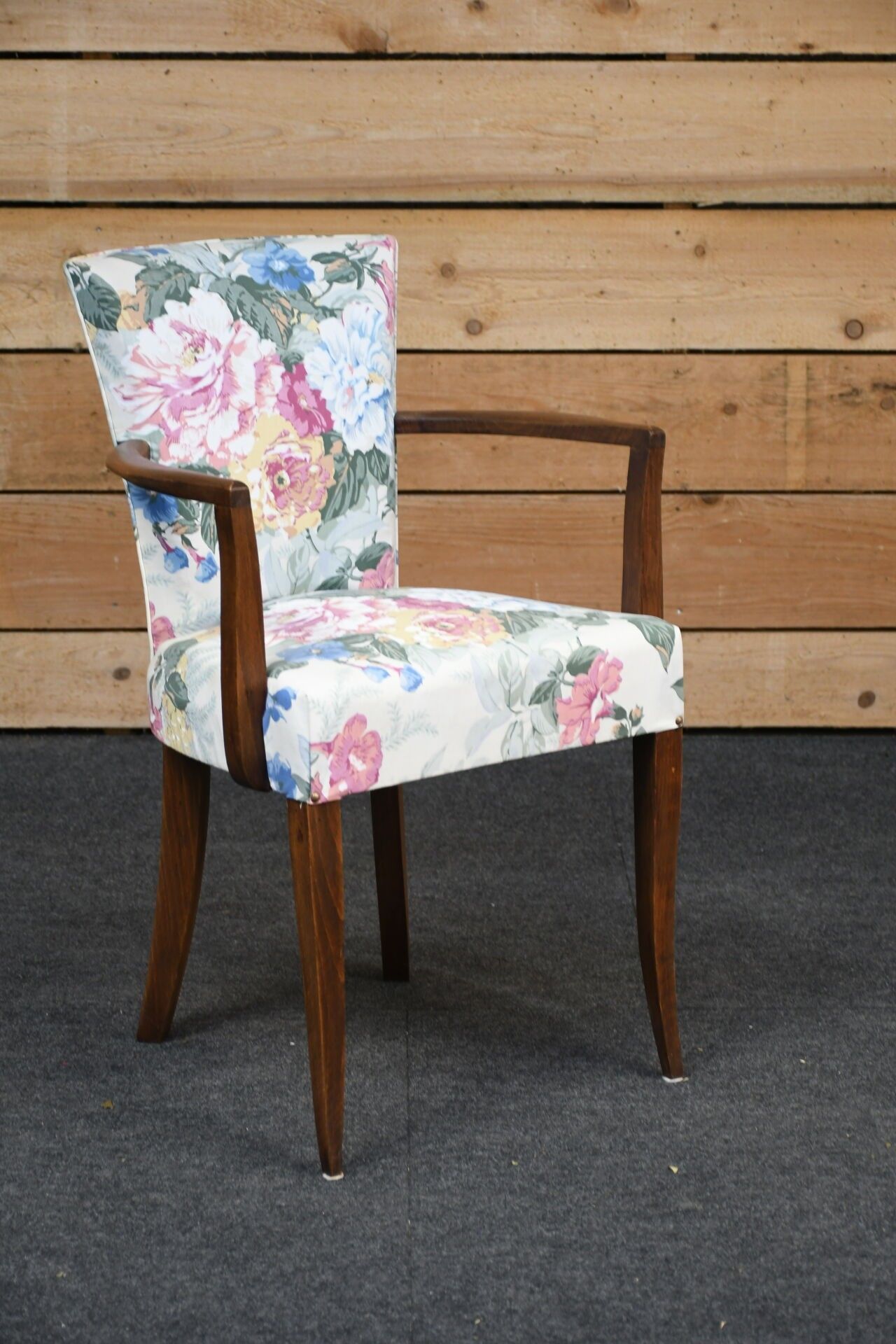 Fauteuil bridge en bois teinté garni de tissu à fleurs.