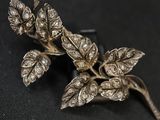 une broche en argent ornée de feuilles sur un fond noir