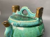 a green teapot with a wooden handle on a table