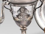 un plateau en argent orné d'un paon, à côté d'une coupe en argent