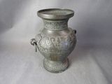 un vase en argent posé sur une surface blanche