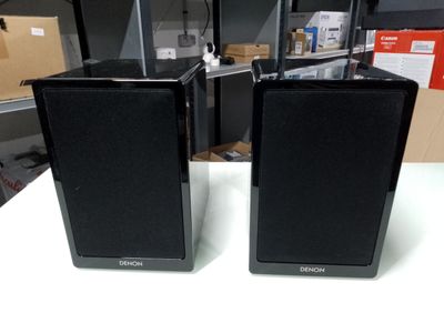 pair of black speakers sitting on top of a table in a room