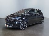 La voiture noire est garée dans une pièce blanche au sol noir.