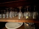 bottles and glasses are lined up on a shelf in a room