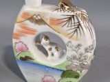 a picture of a vase with a cat on it and a bowl on the side