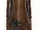 une statue en bois représentant un homme coiffé d'un chapeau