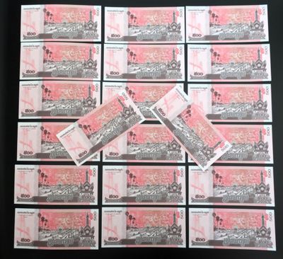 une pile de billets roses et blancs posée sur une table noire