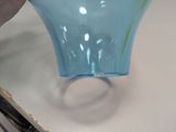 a person holding a blue glass vase on a table