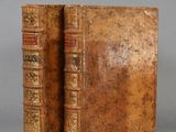 two old books are sitting on top of each other on a table