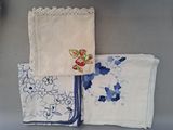 trois morceaux de tissu ornés de motifs brodés, posés sur une table
