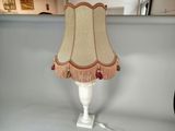 une lampe posée sur une table, avec un pied blanc