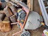 une bétonnière posée à côté d'un tas de bois