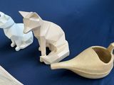 three pieces of paper on a table with a vase and a cat figurine