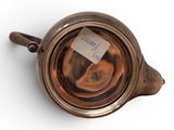 a small teapot with a tag on it