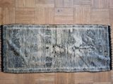 an old rug on a wooden floor with a black and white design