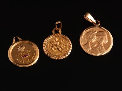 trois pendentifs en forme de pièces d'or sur fond noir, avec un fond noir