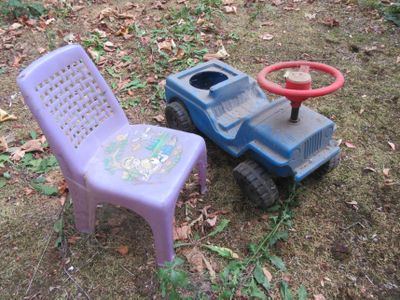 two plastic chairs and a plastic toy truck in the yard