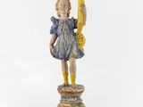 une vieille statue en bois représentant une jeune fille tenant une bougie, posée sur un socle