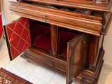 an old wooden cabinet with a red velvet seat in the corner