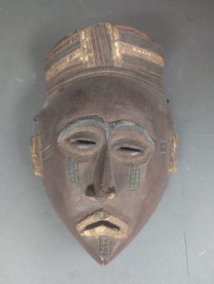 un masque en bois avec un visage brun et un chapeau sur la tête