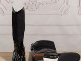 pair of black boots sitting on top of a wooden floor next to a wall
