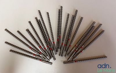Plusieurs vis métalliques sont disposées sur une surface blanche