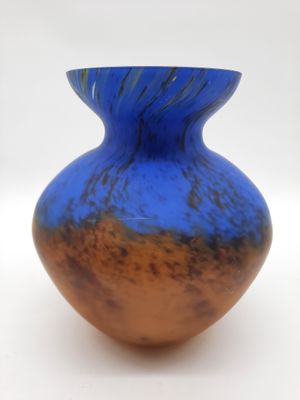 a blue and brown vase sitting on a white surface