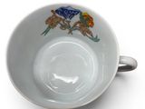 a white cup with a bird on it on a white surface