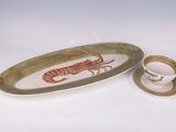 a plate with a lobster on it next to a cup