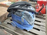 un aspirateur bleu posé sur une palette à côté d'autres articles
