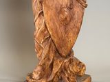a wooden statue of a woman holding a shield