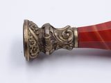 a red vase with a gold handle on a white surface