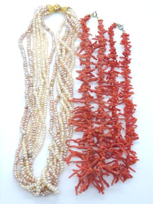 trois colliers de corail et de perles sur un fond blanc
