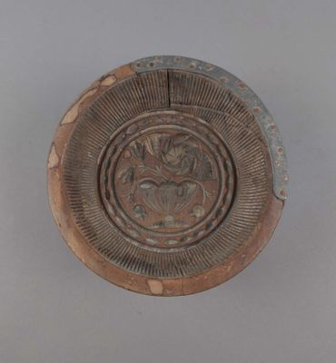 une assiette marron ornée d'un motif sur un fond gris
