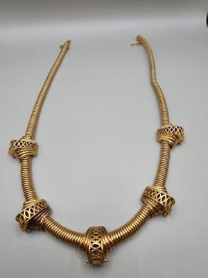 un collier plaqué or orné de perles sur un fond blanc