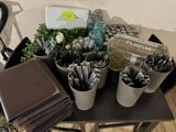 une table sur laquelle se trouvent de nombreux stylos et autres fournitures de bureau