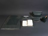 a black leather desk set with a pen, notebook, and pen holder