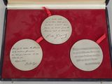 two silver medallions in a red box with a red ribbon