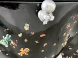a large black bowl with a handle that has a flower design on it