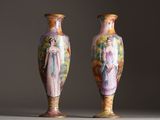 pair of vases with painted figures on them sitting on a table