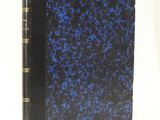 an old book with a blue cover sitting on top of a white table