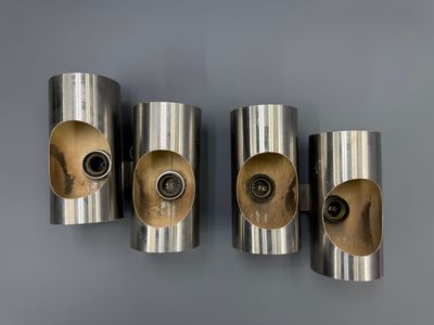 three silver metal wall sconces mounted on a gray wall