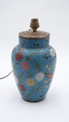 un vase bleu orné de fleurs, surmonté d'une lampe